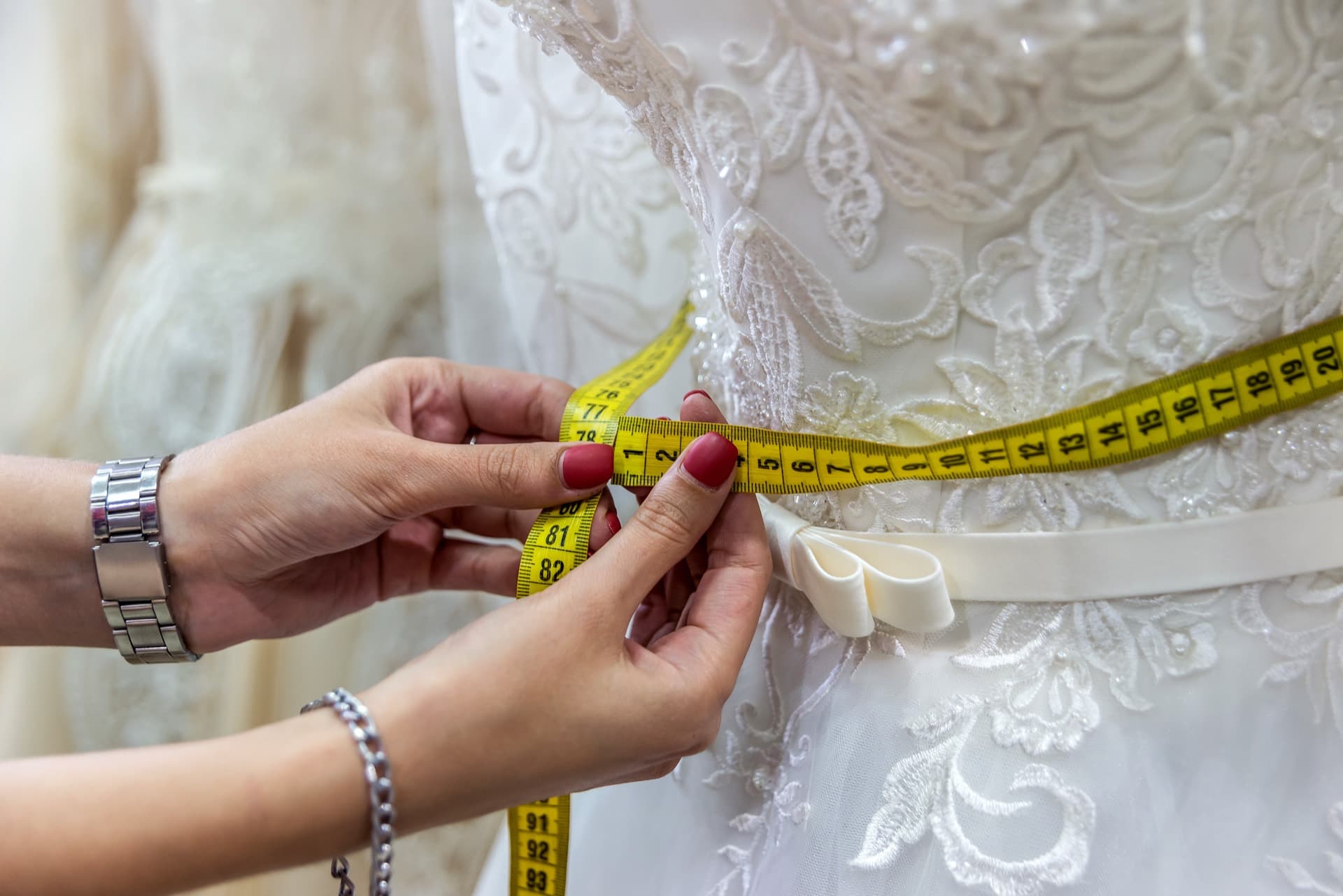 Seamstress measuring the waist of a wedding dress during a bridal alteration fitting in Los Angeles